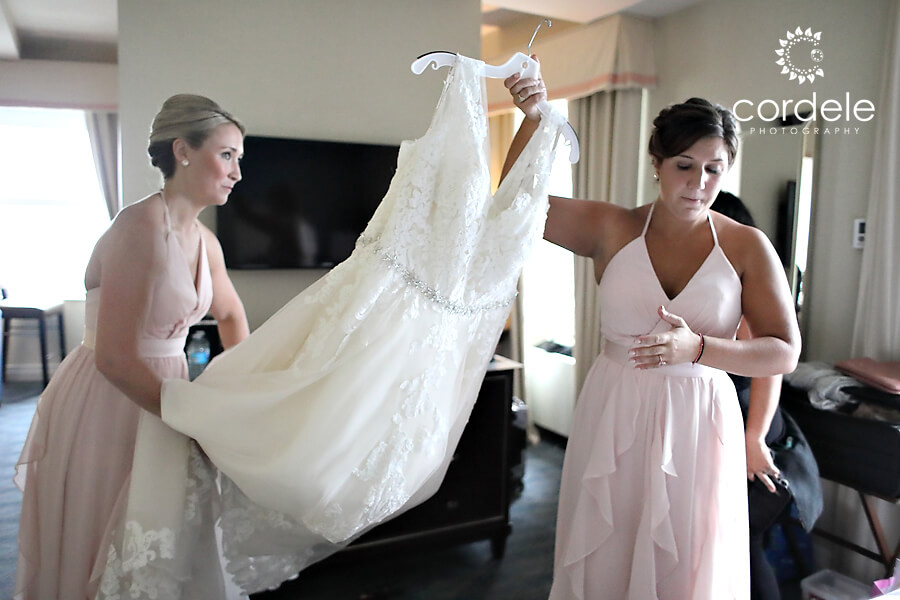 Two brides maids wearing blush pink carry wedding dress